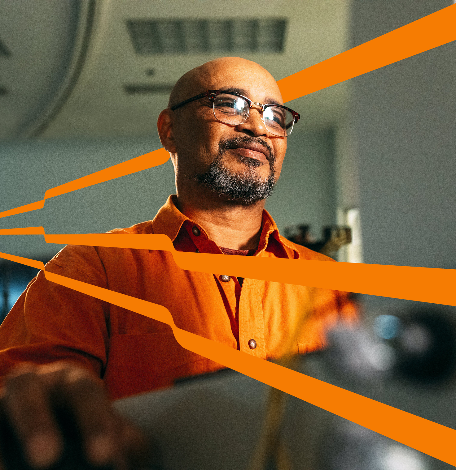 Stock photo of a person with glasses working on a computer, with orange lines extending from the screen.