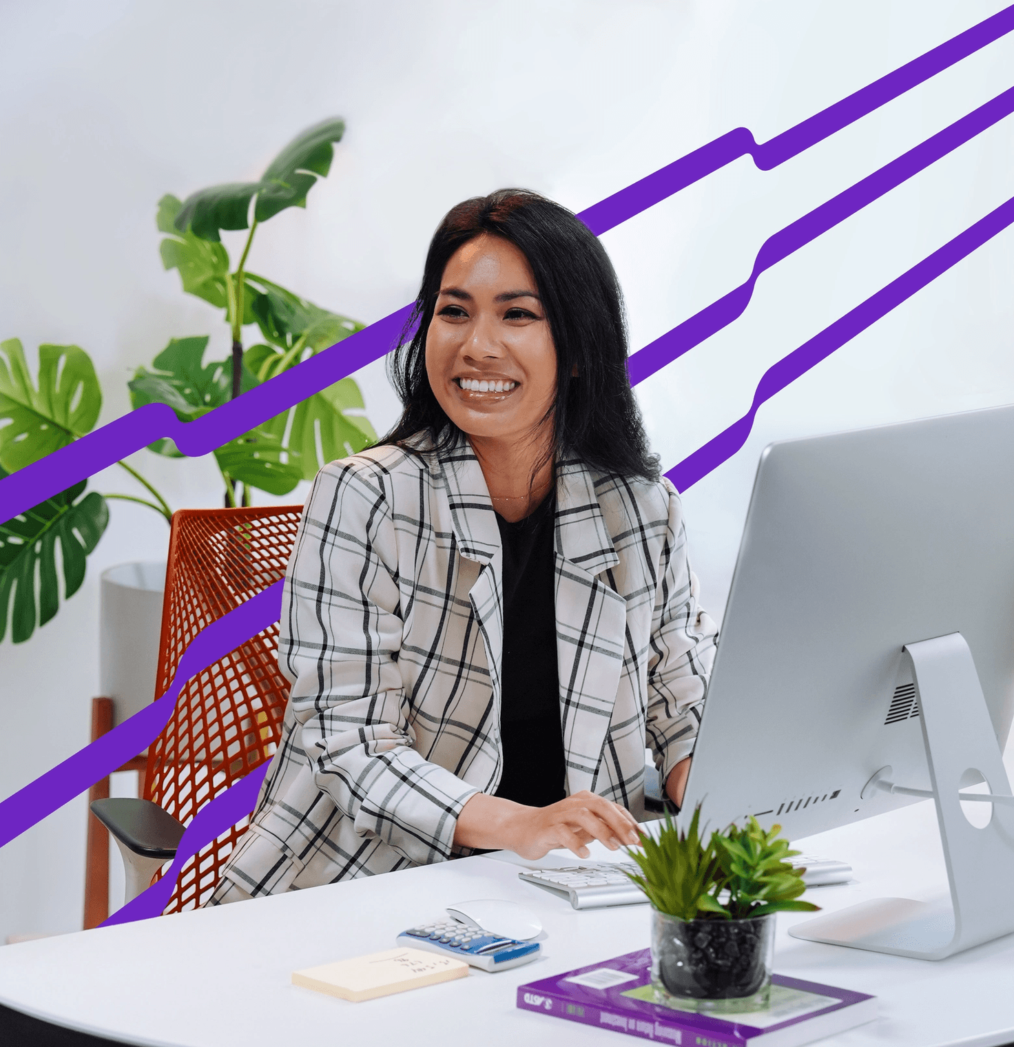 A woman sits at a desk, smiling while looking at a computer monitor. The desk features notepads, a pen, and a lush plant. Purple diagonal lines extend in the background.