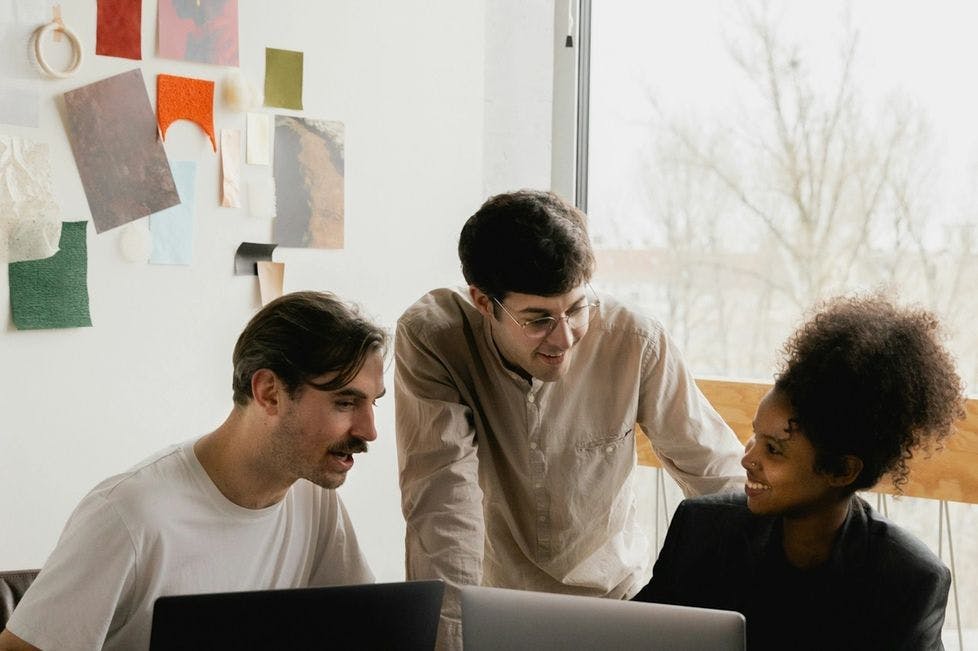 Three people collaborating in a bright design office with laptops