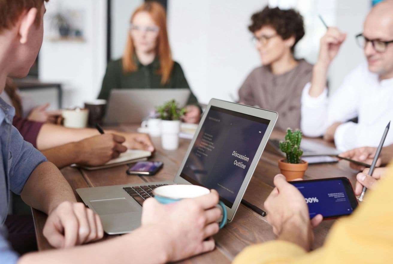 Vignette of a laptop with people collaborating in the background