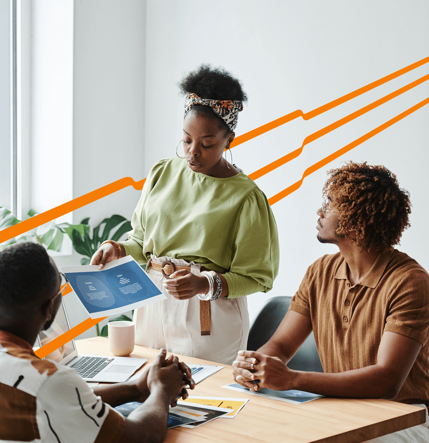 Stock photo of three people having a meeting in a modern office. A laptop, notebook, and mug are on the table. Orange lines are extending in the background.