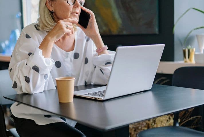 Older Woman talking on the phone and working at her computer in the office