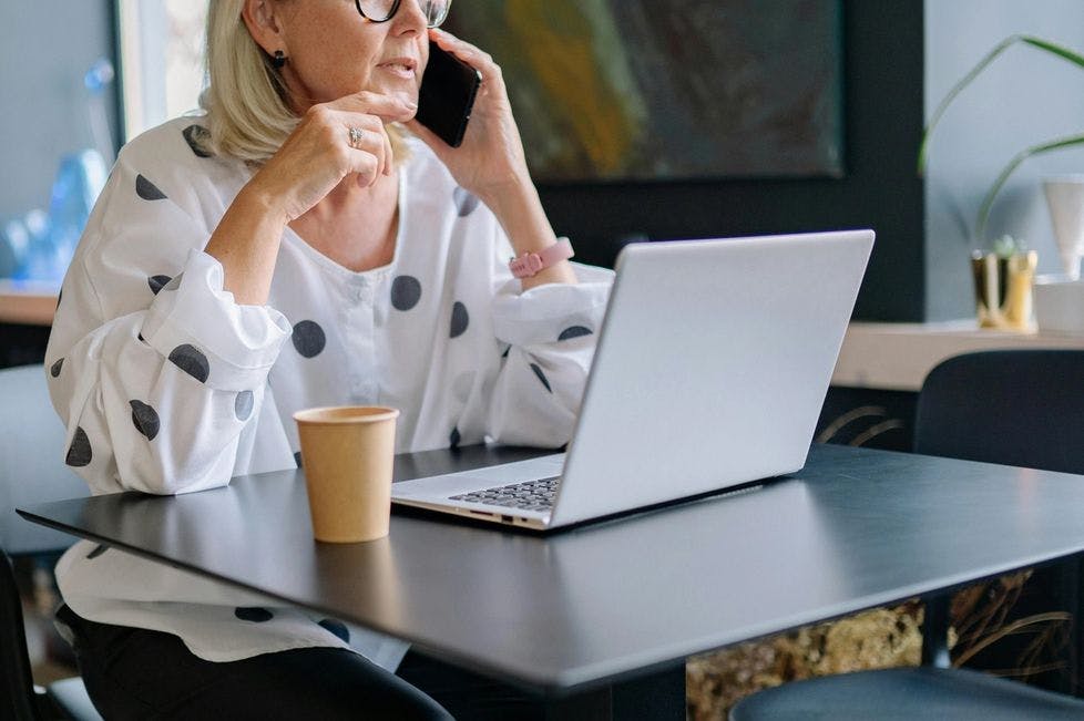 Older Woman talking on the phone and working at her computer in the office