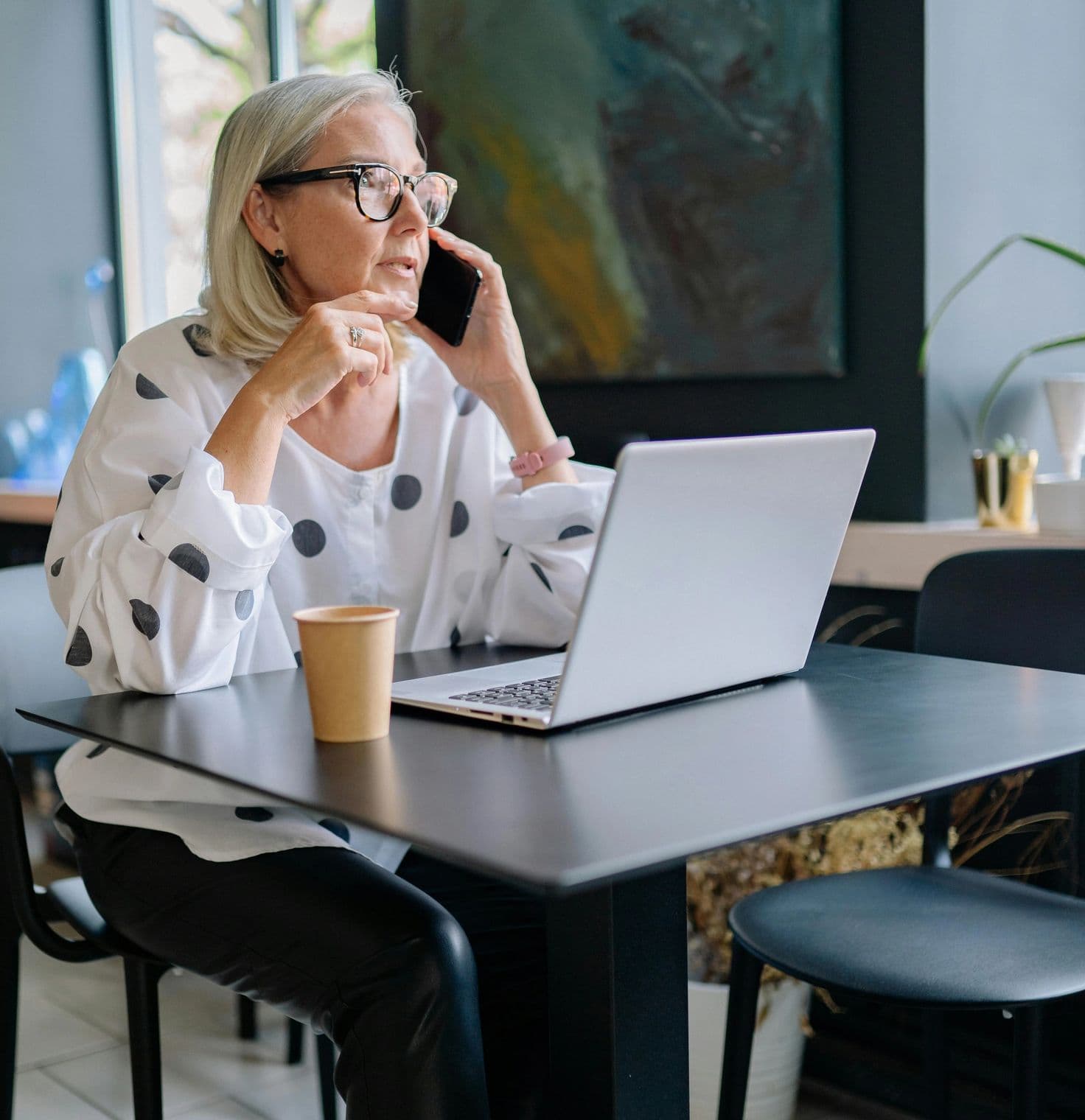 Older Woman talking on the phone and working at her computer in the office