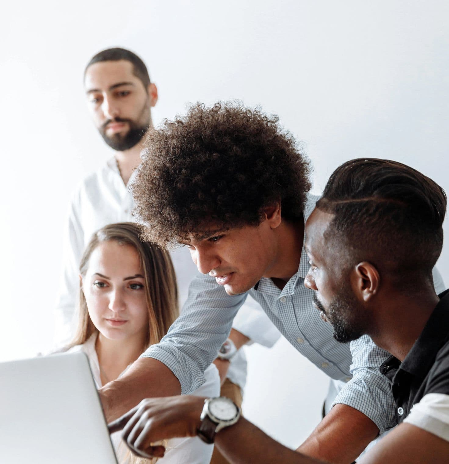 Portrait shot of four people collaborating closely on a laptop