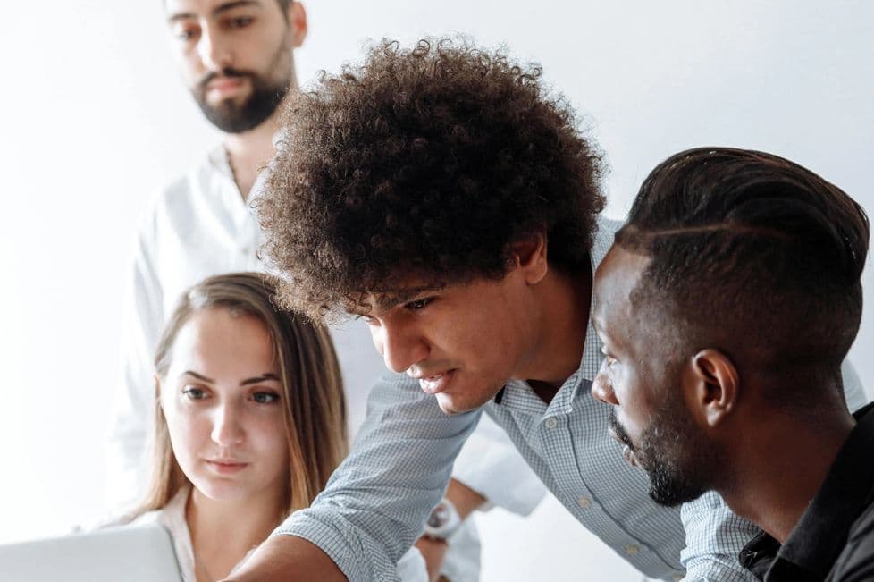 Portrait shot of four people collaborating closely on a laptop