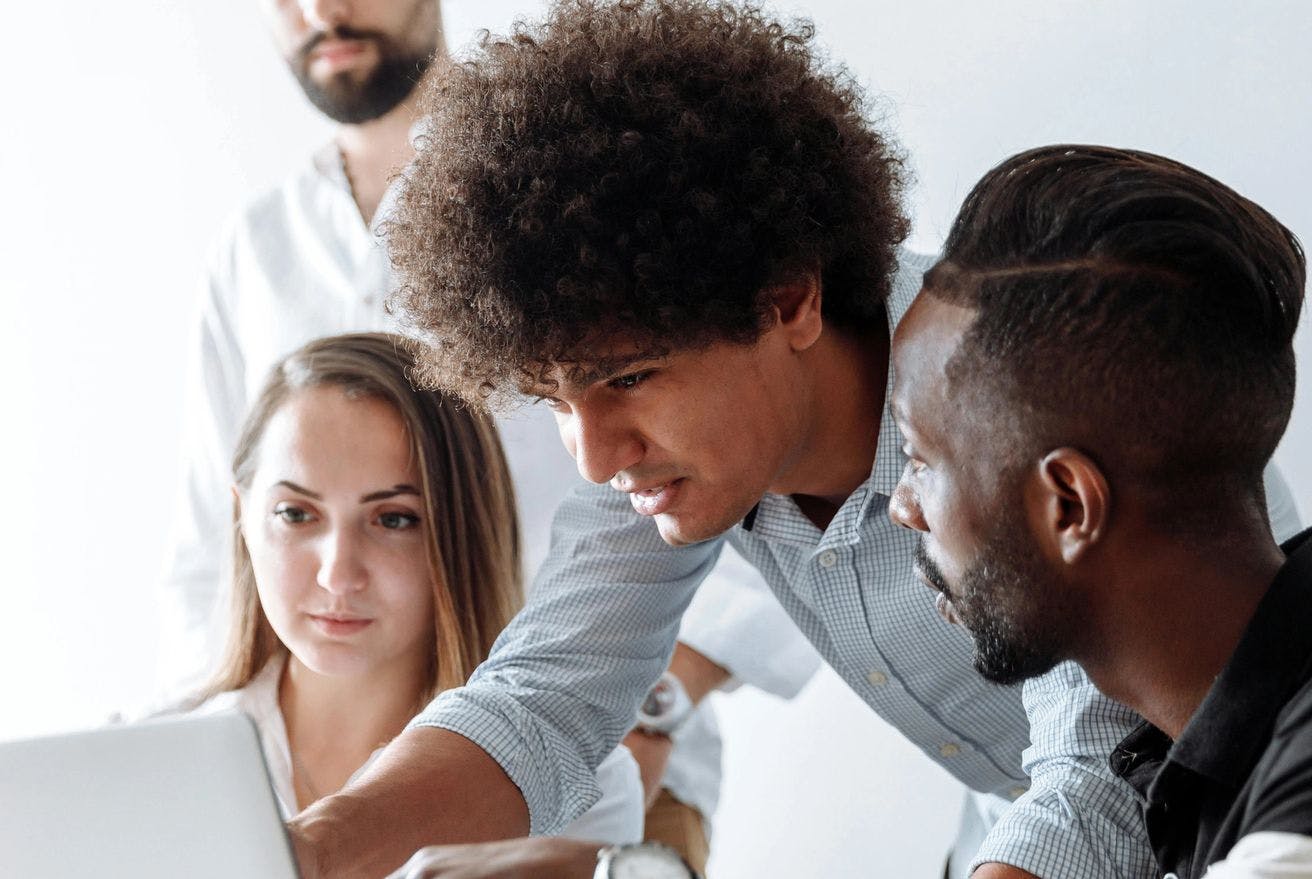 Portrait shot of four people collaborating closely on a laptop