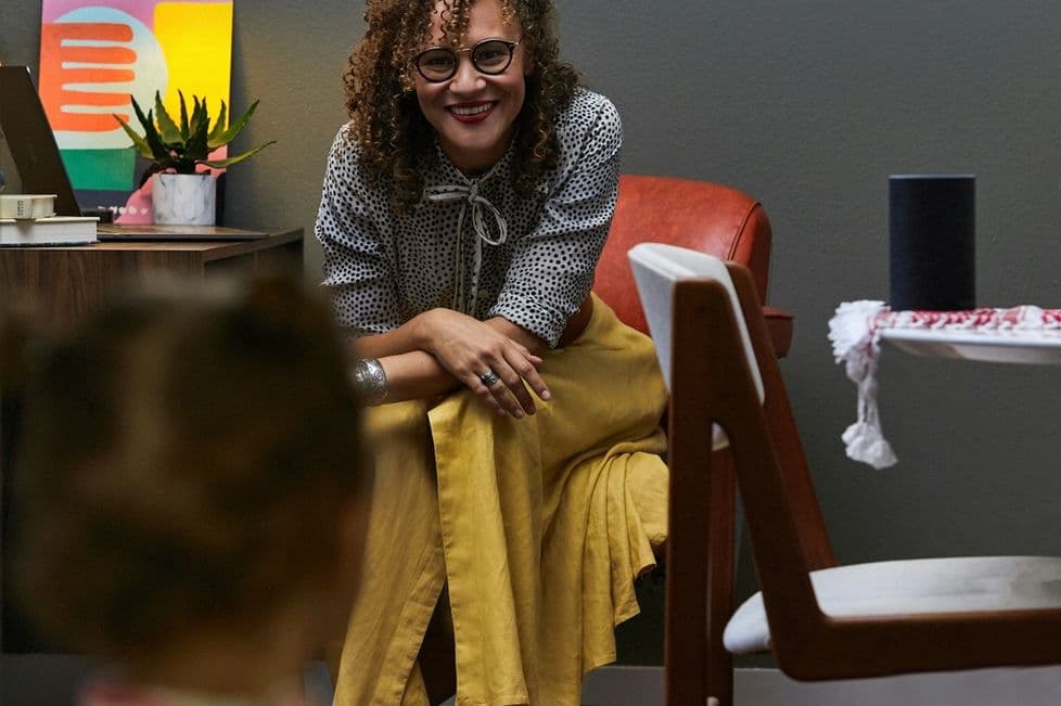 Woman in a yellow skirt working at home with a toddler in the foreground