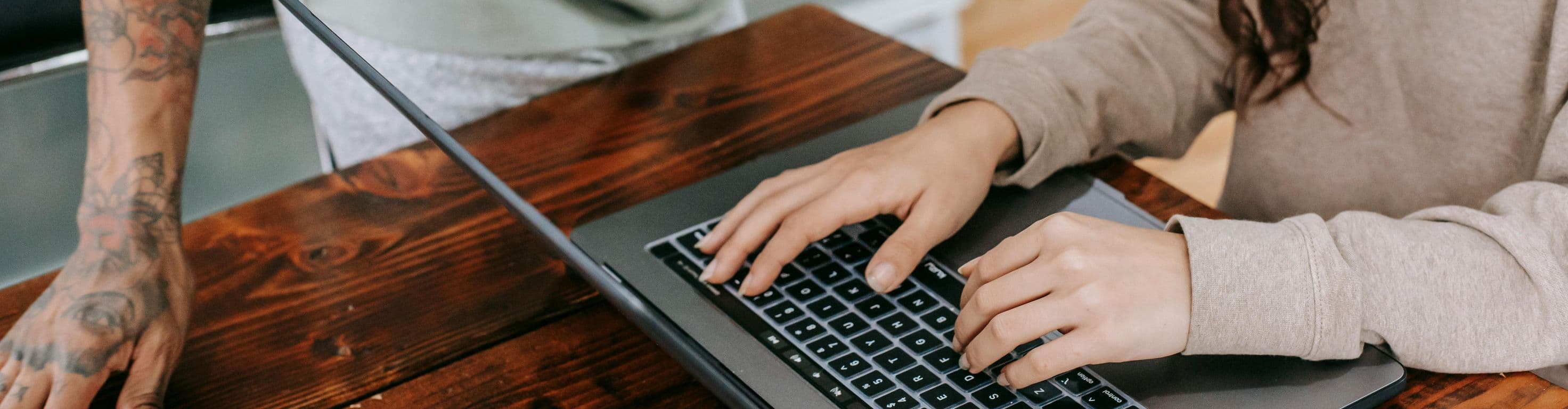 Close up of hands around a computer with a coffee cup