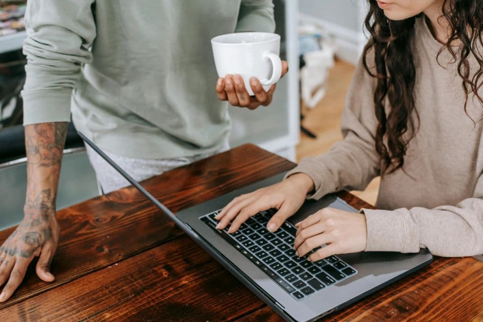 Close up of hands around a computer with a coffee cup