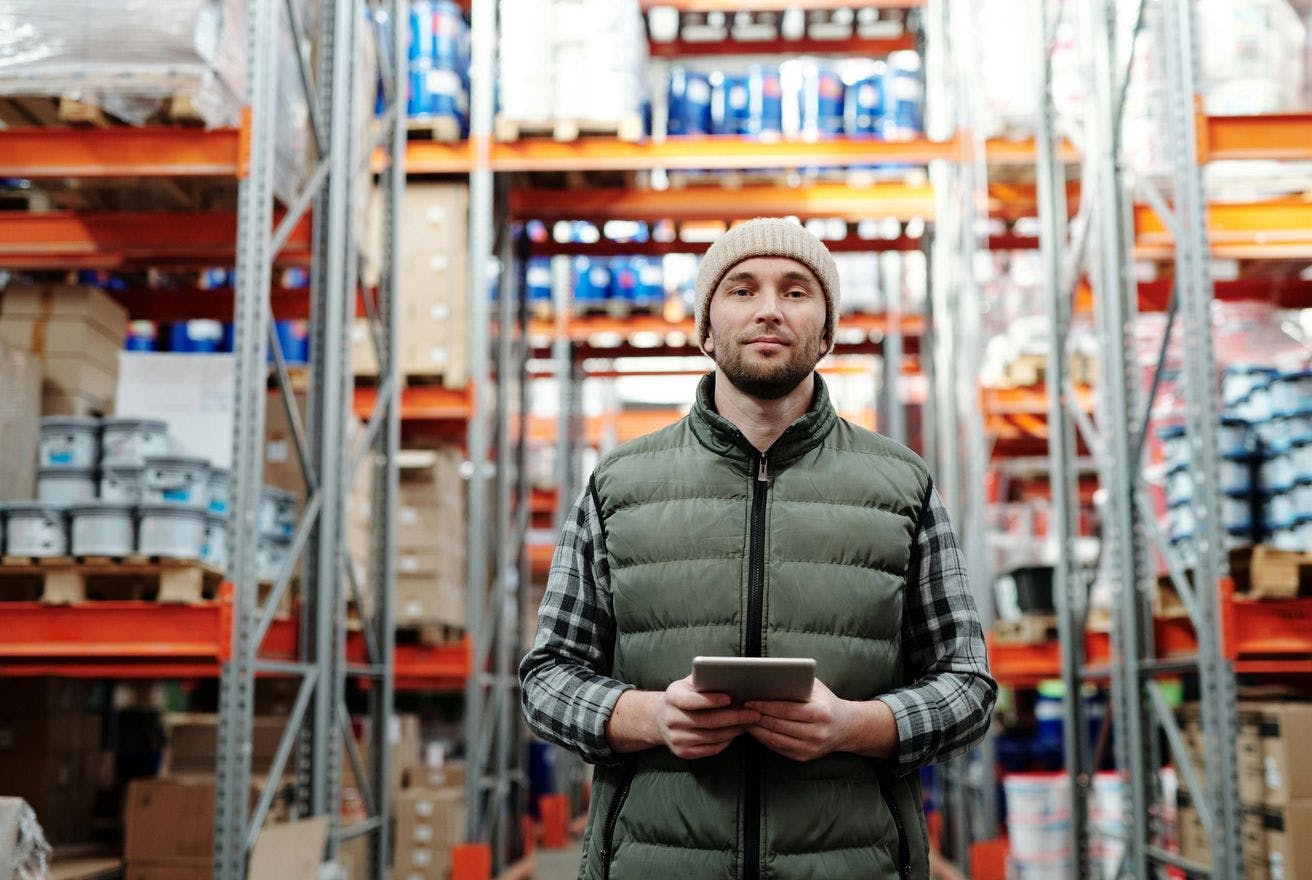 Man with a teblet in orange warehouse looking at the camera