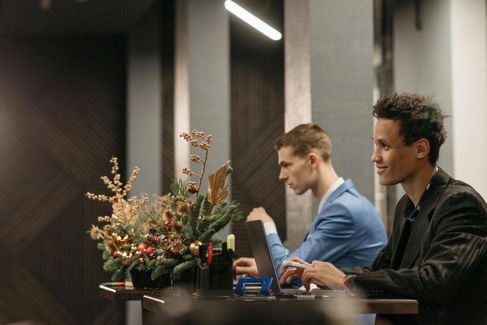 Two men working at a desk with a holiday floral arrangement