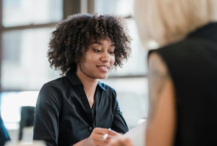 Woman in a black shirt working closely with a friend