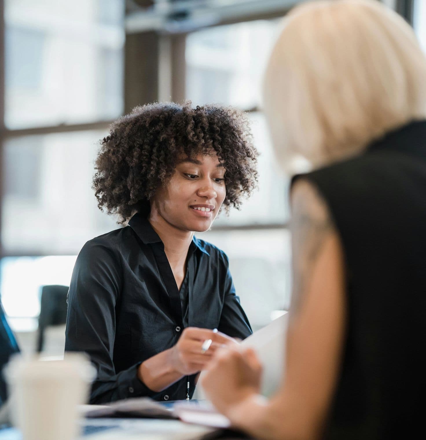 Woman in a black shirt working closely with a friend