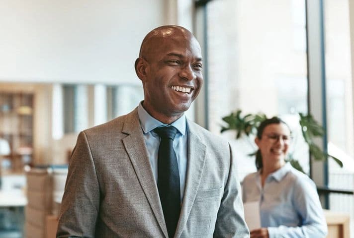 Man and woman in a bright office  smiling at someone outside of the frame