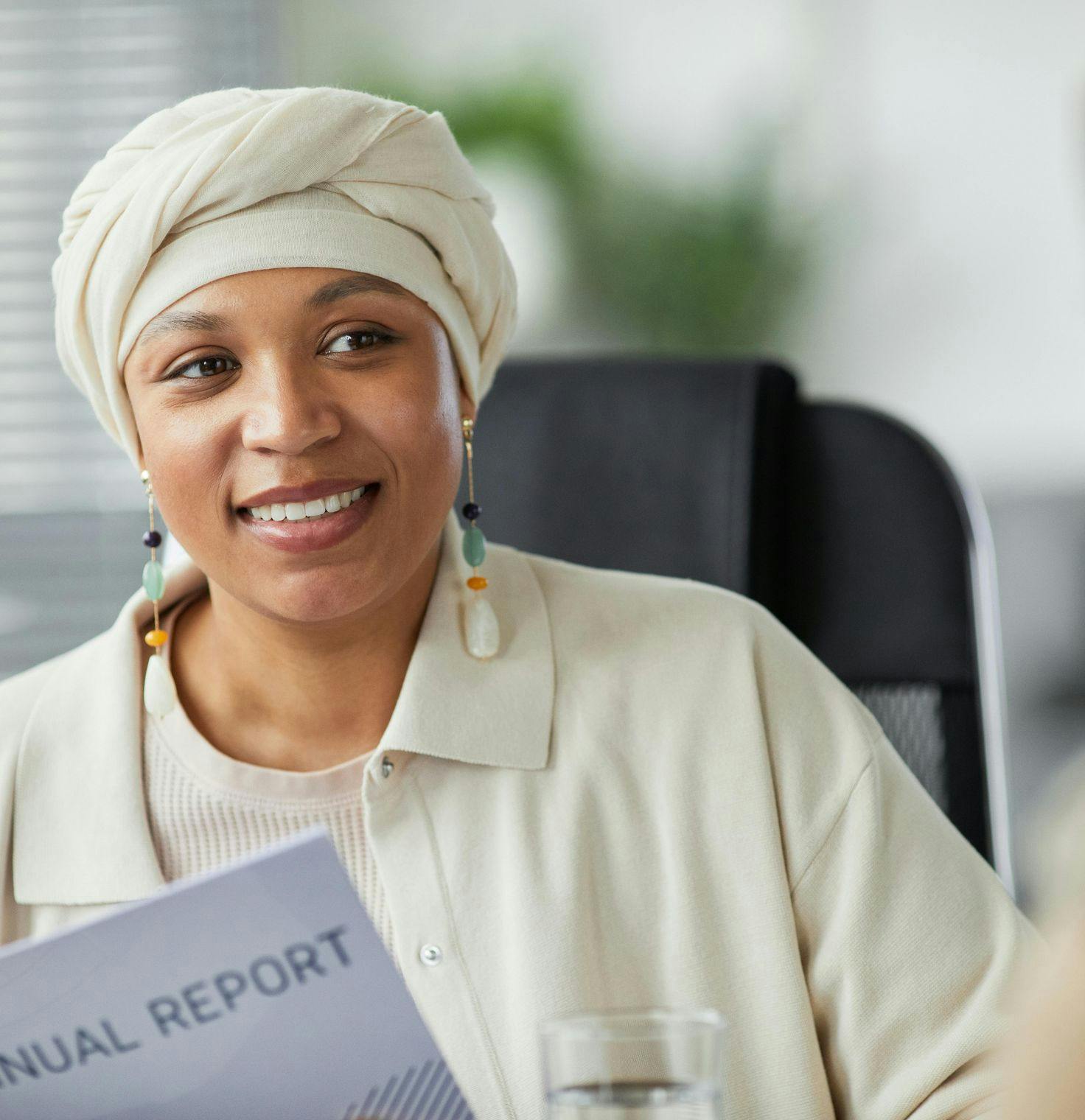 SMiling woman in a turban sitting in an office reviewing a report