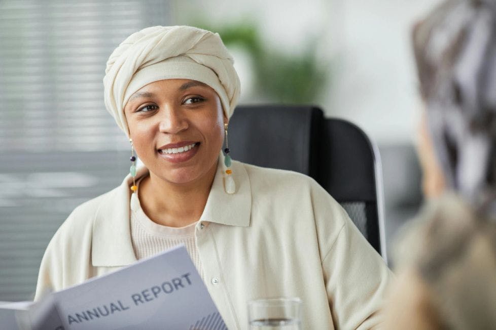 SMiling woman in a turban sitting in an office reviewing a report