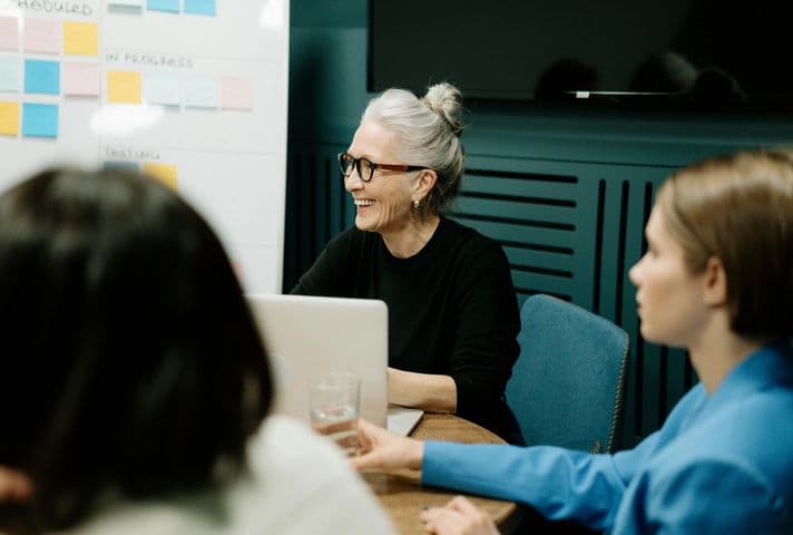 Older woman collaborating at a table and using a computer