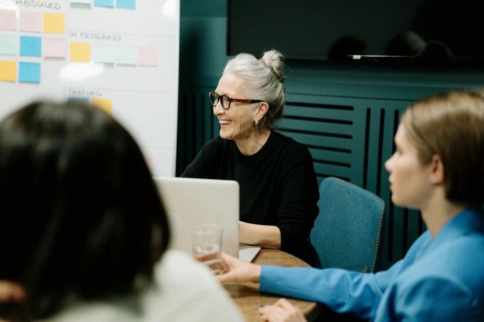 Older woman collaborating at a table and using a computer