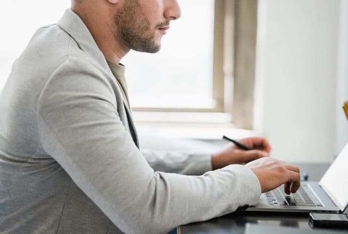 Side shot of man working at computer and thinking